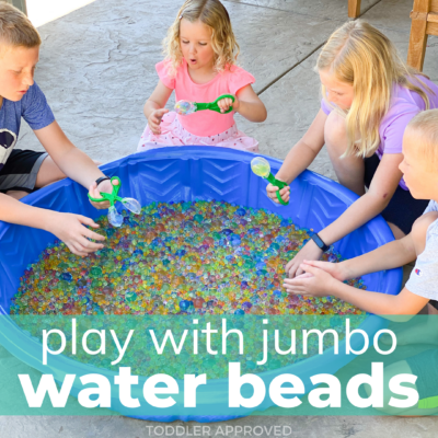 four kids playing with jumbo water beads in a blue baby pool